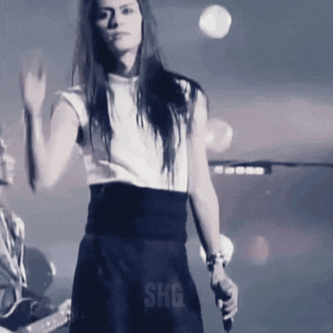 a woman singing into a microphone with shg written on the bottom right