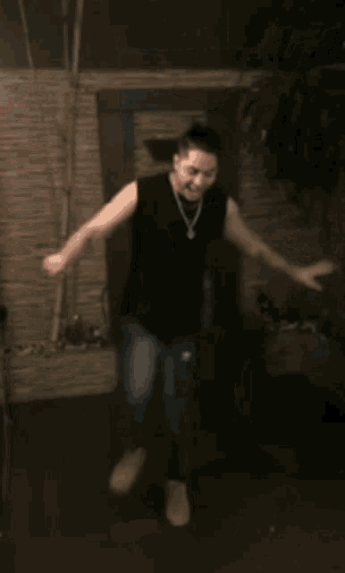 a man in a black tank top is dancing in front of a mirror .