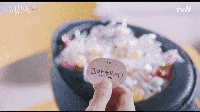 a person is holding a piece of paper with korean writing on it