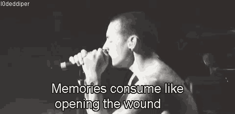 a man singing into a microphone with the words memories consume like opening the wound above him