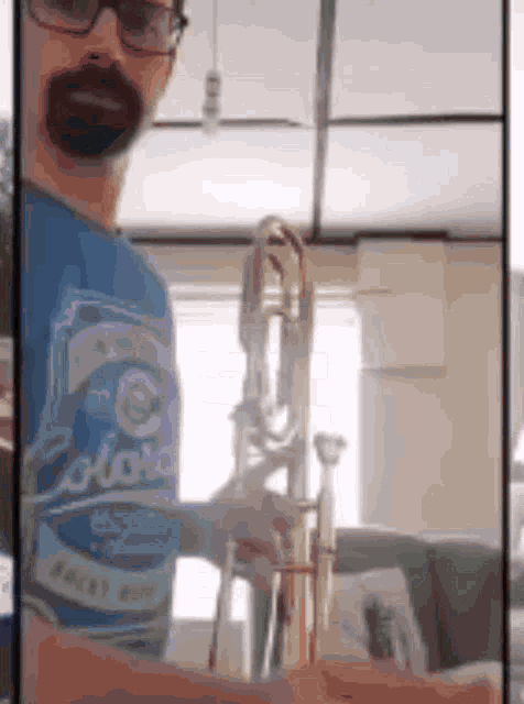 a man in a blue shirt is holding a trombone in his hands .