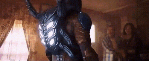 a man in a superhero costume is standing in a room with a group of people .