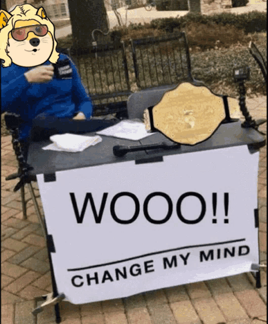 a man sits at a table with a sign that says wooo on it