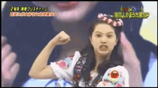 a woman with a flower crown on her head is flexing her muscles on a tv show