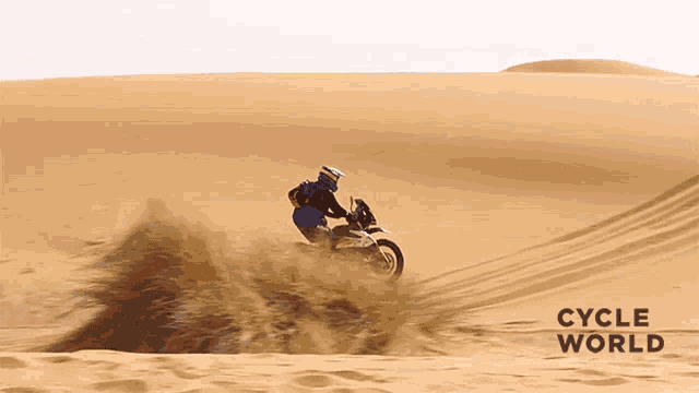 a person riding a dirt bike in the desert with cycle world written on the bottom right
