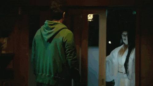 a man in a green shirt is being attacked by a woman in a white robe