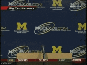 a man is holding a piece of paper in front of a m logo
