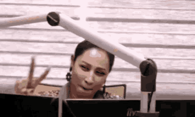 a woman is giving a peace sign while sitting in front of a computer .