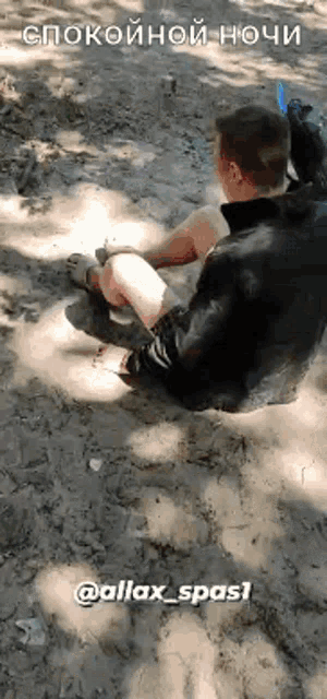 a man is sitting on the ground in the dirt with a foreign language written on the bottom .