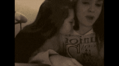 a woman is holding another woman 's hand in her mouth while they are sitting next to each other .