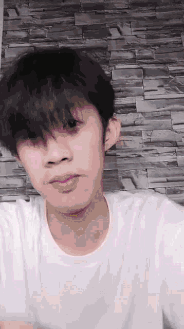 a young man in a white shirt is making a funny face