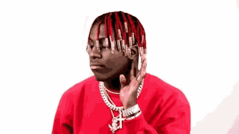 a man with red hair is talking on a cell phone while wearing a red sweater .