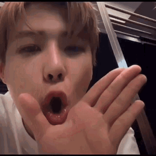 a close up of a man making a funny face with his mouth open and his hand in his mouth .