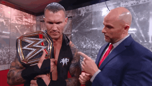 a man in a suit and tie is holding a wrestling belt with the letter w on it