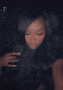 a blurry picture of a woman covering her face with her hand in a dark room .