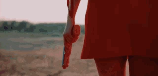 a woman in a red dress is holding a red toy gun in her hand .