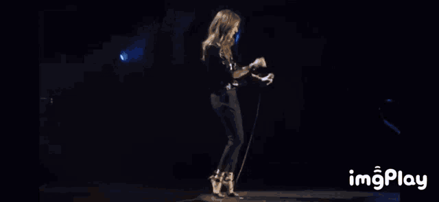 a woman is dancing on a stage with the words imgplay in the bottom right corner