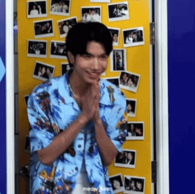 a young man in a blue shirt is standing in front of a yellow door with pictures on it .