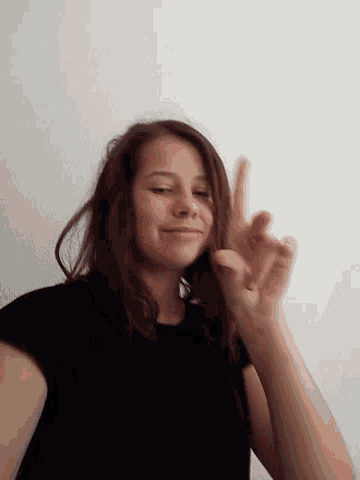 a woman in a black shirt making a peace sign