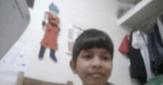 a young boy is standing in a room with a drawing of a dragon ball z character on the wall .