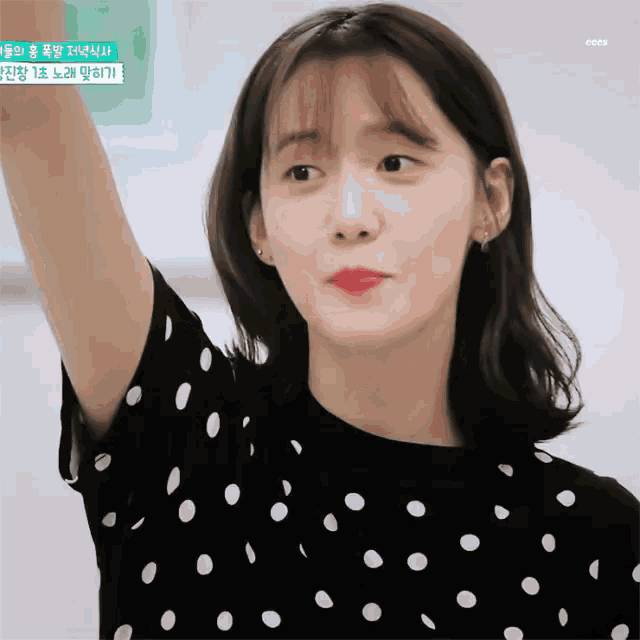a woman wearing a black and white polka dot shirt with her arm up
