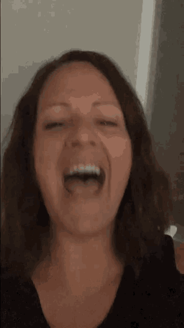 a woman is laughing with her eyes closed and her mouth open