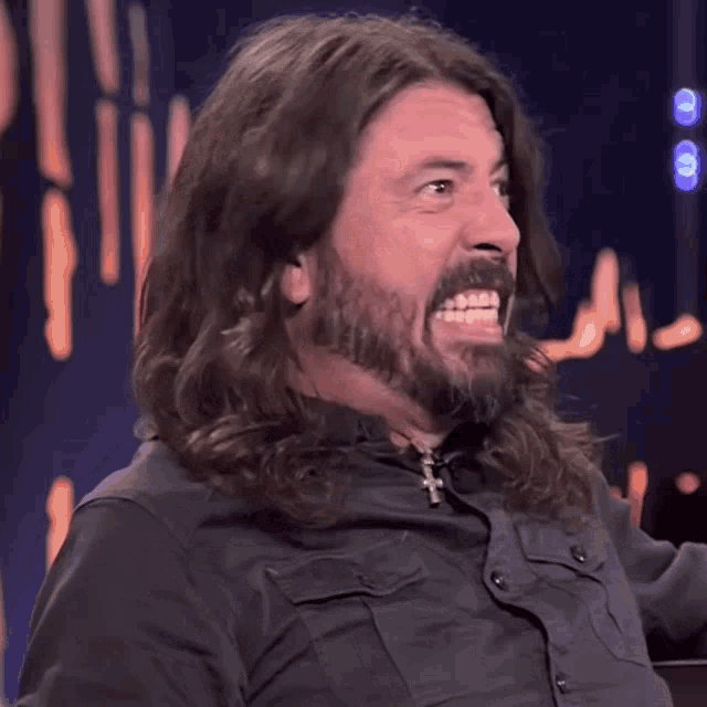 a man with long hair and a beard smiles at the camera
