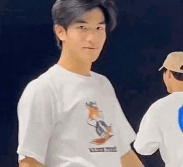 a young man wearing a white t-shirt with a fox on it is standing next to another young man .