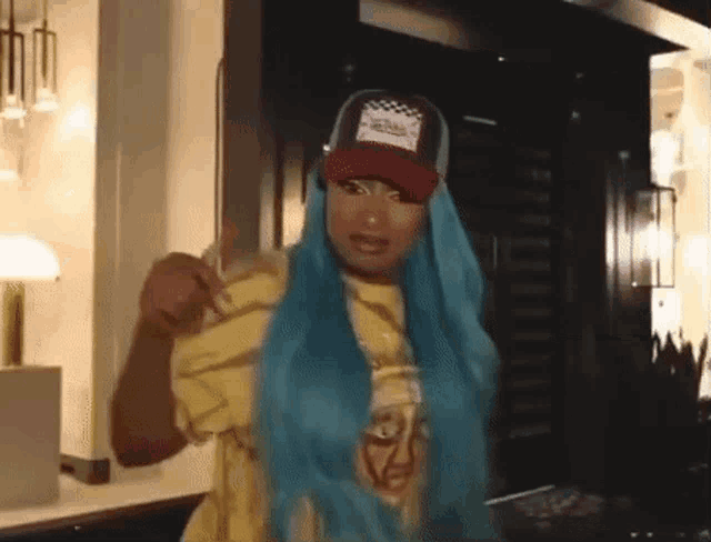a woman with blue hair and a red hat is wearing a yellow shirt and a red hat .