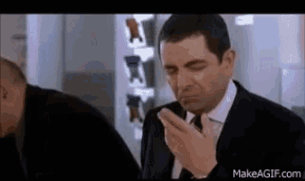 a man in a suit and tie is smoking a cigarette in a room .