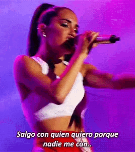 a woman singing into a microphone with the words salgo con quien quiero porque nadie me con on the bottom