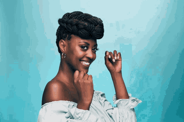 a woman with a braided hairstyle is smiling and holding her hand to her chin