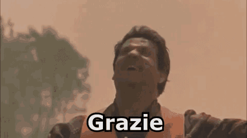 a man is standing with his arms outstretched and the word grazie written on his face .