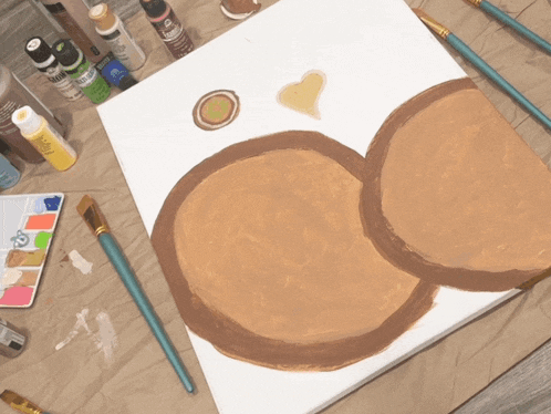 a bottle of acrylic paint sits on a table next to a painting on a canvas