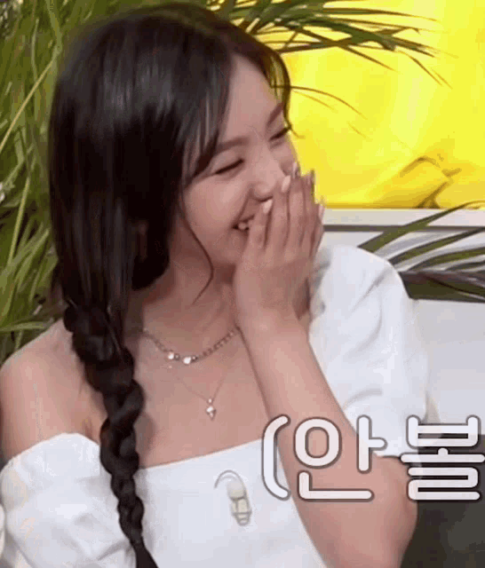 a woman in a white top is laughing and covering her mouth