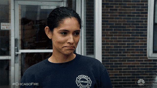 a woman wearing a chicago fire department shirt stands in front of a building