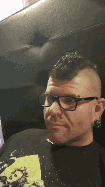 a man with glasses and a mohawk has a tattoo on his face