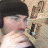 a man wearing headphones and a beanie is drinking from a bottle of wine .