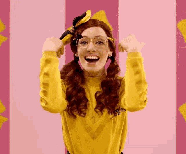 a woman wearing glasses and a yellow shirt that says the wiggles