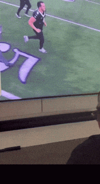 a man is running on a football field with the letter t on it