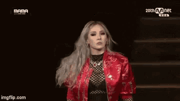a woman in a red jacket is dancing on a stage with a group of people .