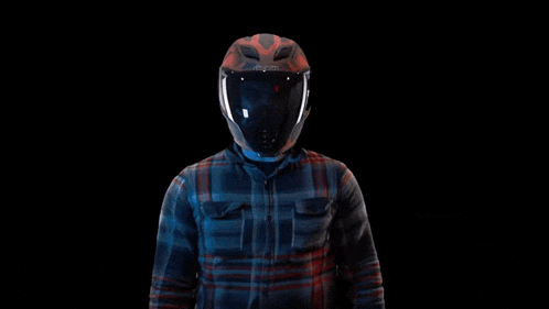 a man wearing a helmet and a plaid shirt is pointing at something .