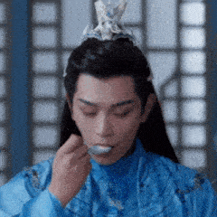 a man wearing a blue costume and a crown is eating something with a spoon