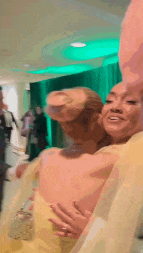 a woman in a yellow dress is hugging another woman in a white dress