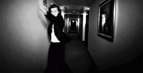 a man in a suit is dancing in a hallway in a black and white photo .