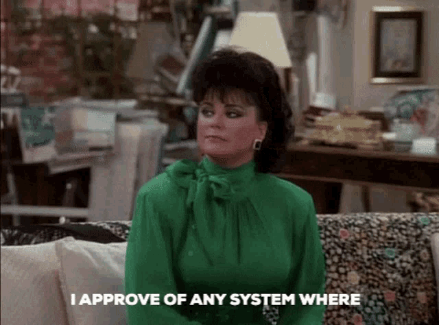 a woman in a green shirt sits on a couch with the words i approve of any system where below her