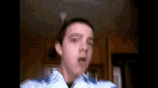 a boy in a blue and white shirt is making a funny face .