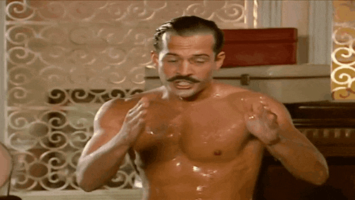 a shirtless man with a mustache is standing in a room