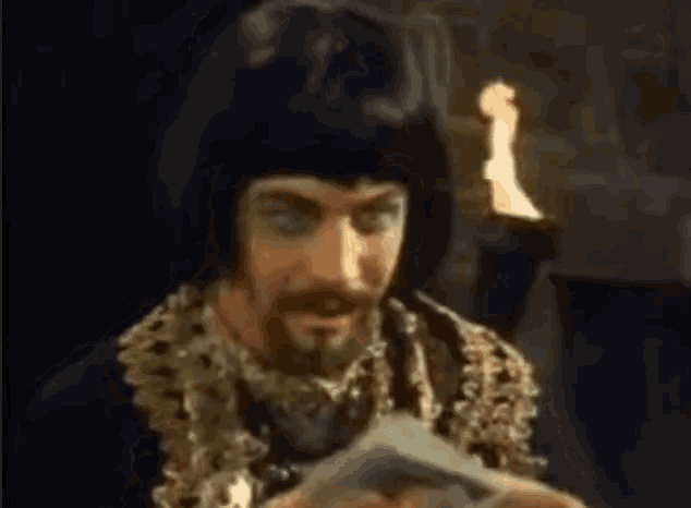 a man with a beard is holding a piece of paper in front of a torch .
