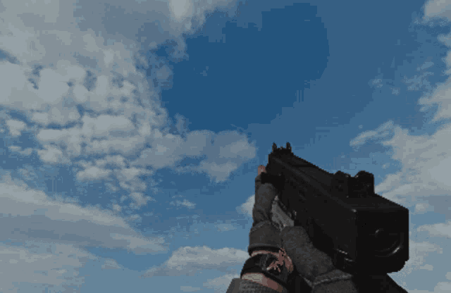 a person is holding a gun in front of a cloudy blue sky